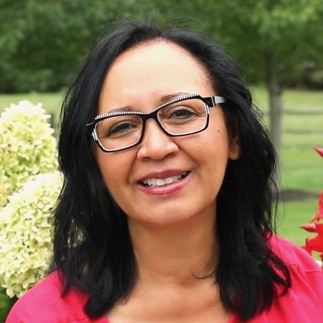 Grace wearing glasses in a pink shirt and happy.