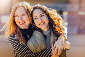 Smiling Mother hugging teen daughter