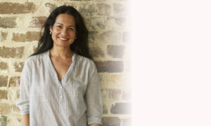 Tess Masters smiling in front of a brick wall