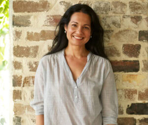 Tess Masters smiling in front of a brick wall