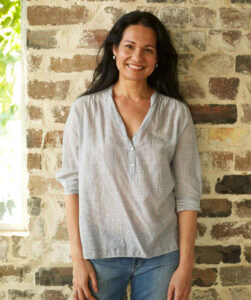 Tess Masters smiling in front of a brick wall