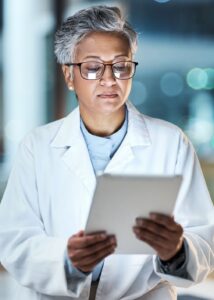 Medical, research and night with doctor and tablet for planning, medicine and schedule. Technology, review and digital with senior woman reading report for healthcare, science and life insurance news