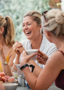 Mature women are socialising over breakfast in the courtyard of their holiday villa in Italy.