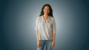 A standing smiling Tess in front of a blue background