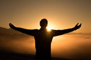 Silhouette of a man doing a yoga pose in front of a beautiful sunset