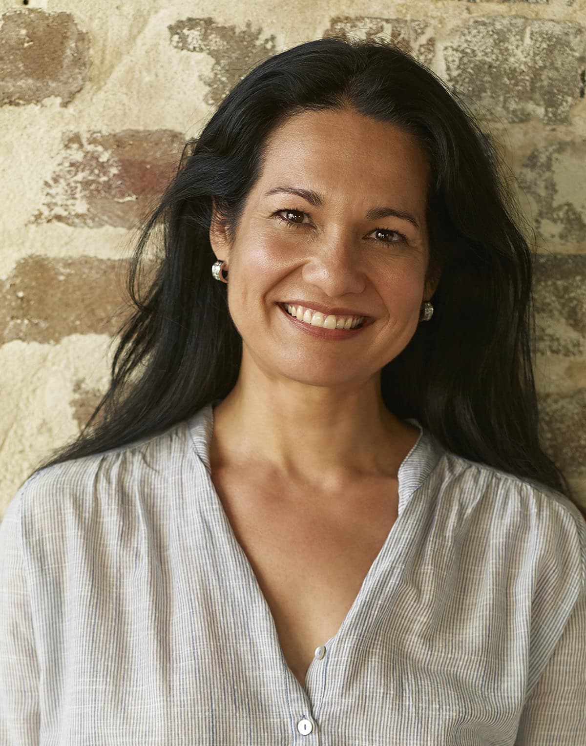 Tess Masters smiling in front of a brick wall