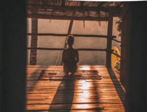 Silhouette of a women doing a yoga pose in a tree house in front of a beautiful sunset