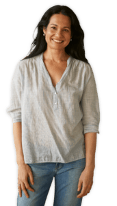 Tess Masters standing and smiling in a breezy button down shirt and jeans