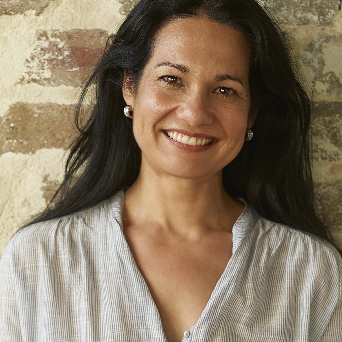Tess-Masters-Headshot Tess Masters smiling in front of a brick wall